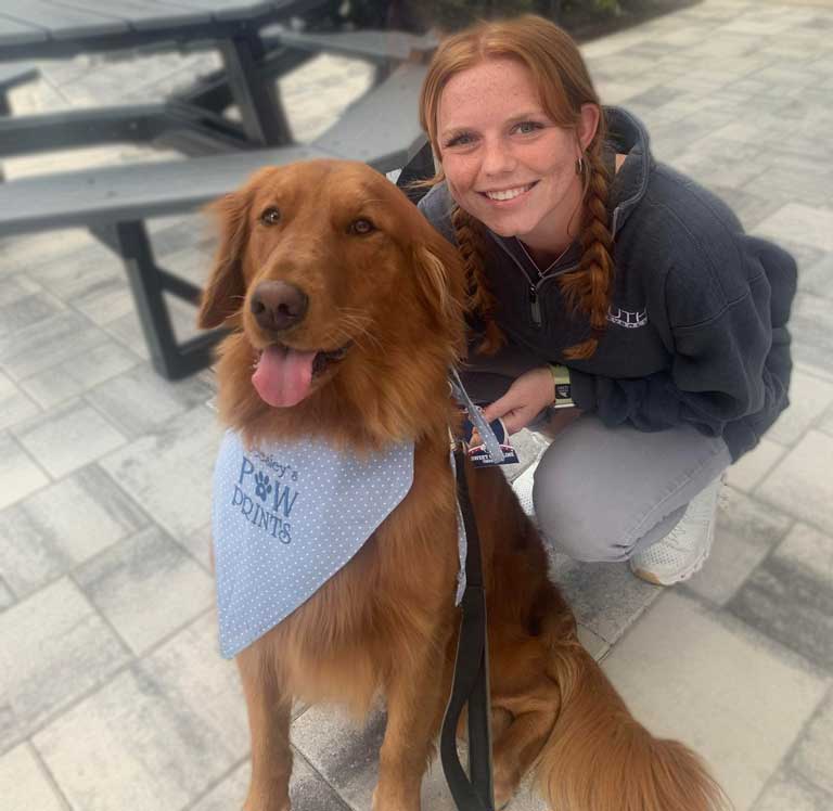 FGCU Student posing with Caroline the Therapy Dog